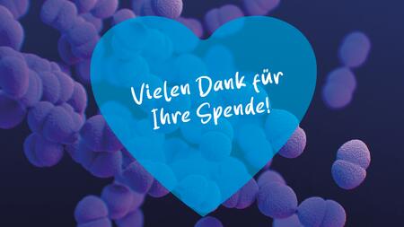 Das Bild zeigt eine mikroskopische Darstellung von kugelförmigen Bakterien in verschiedenen Blautönen auf einem dunklen Hintergrund. Im Vordergrund ist ein transparentes, herzförmiges Overlay in einem helleren Blau, das den Text „Vielen Dank für Ihre Spende!“ in weißer, handschriftlich wirkender Schrift enthält.