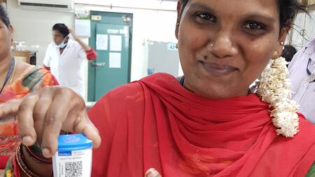 An Indian female lab technician holds the test cartridge tested in the study in her right hand.