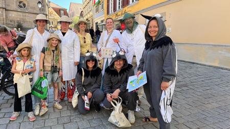 Gruppe von Erwachsenen und Kindern in Malaria- und Mückenkostümen auf dem Tübinger Regionalmarkt.