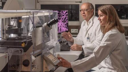Prof. Percy Knolle and first author Dr Miriam Bosch in front of a fluorescence microscope in the lab