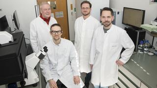 Prof Ulrich Kubitscheck, Jan-Samuel Puls, Dominik Brajtenbach and Dr Fabian Grein (from left to right), all in white lab coats, photographed as a group in the lab.