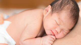 Auf dem Bauch (und der nackten Haut eines nicht-gezeigten Menschen) liegendes Neugeborenes
