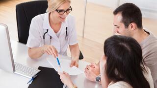 Female doctor in consultation with a female and a male person