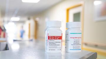 Zwei Behälter mit antiretroviralen Kombinationspräparaten mit den Bezeichnungen „Darunavir/Cobicistat/Emtricitabine/Tenofoviralafenamide” und „Bictegravir/Emtricitabine/Tenofoviralafenamide” stehen auf einer Ablage in einem hellen Krankenhausflur.