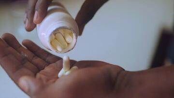 Pills dropping from a medicine bottle into the palm of a hand