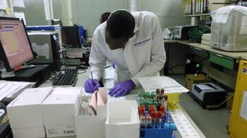 Labor des US Military HIV Research Program (MHRP), mit zwei Labormitarbeitern und Arbeitsplätzen mit Computern, Laborgerätschaften und Blutprobenröhrchen. 