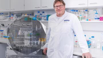 Prof. Stephan Urban im Labor; links im Bild ist die Trophäe des Chris McGuigan-Preises zu sehen.
