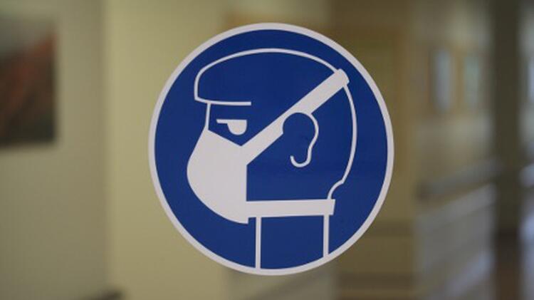 Sticker on a glass pane with a schematic representation of a head wearing a respirator mask in side view